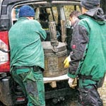 Mitarbeiter des Friedhofes laden das reparierte Taufbecken aus
